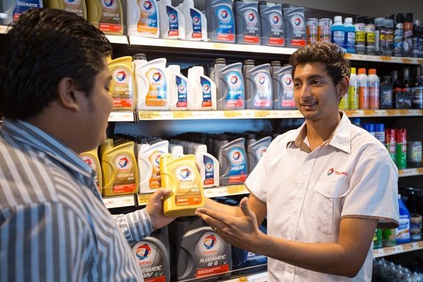 Dans la boutique Bonjour de la station-service Laucala Beach, un employé conseille les lubrifiants Total à un client.